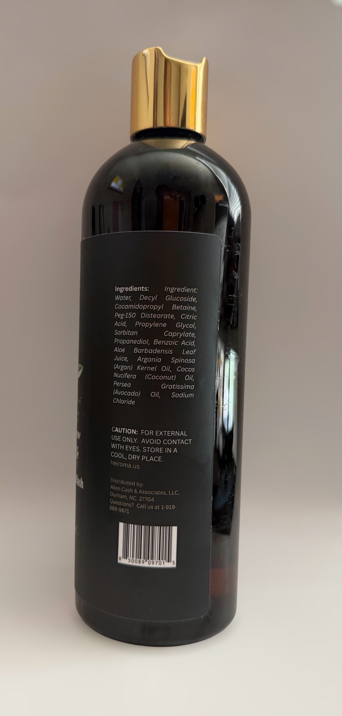 A dark amber bottle with a shiny gold cap, showing the back label with ingredients and a barcode, set against a plain light background.
