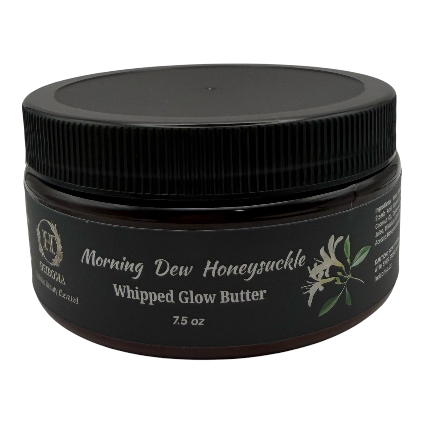 A jar of Morning Dew Honeysuckle Whipped Glow Butter by Heiroma. The product is in a dark amber glass jar with a black ribbed screw-on lid and a black label featuring white text and a small white flower illustration.