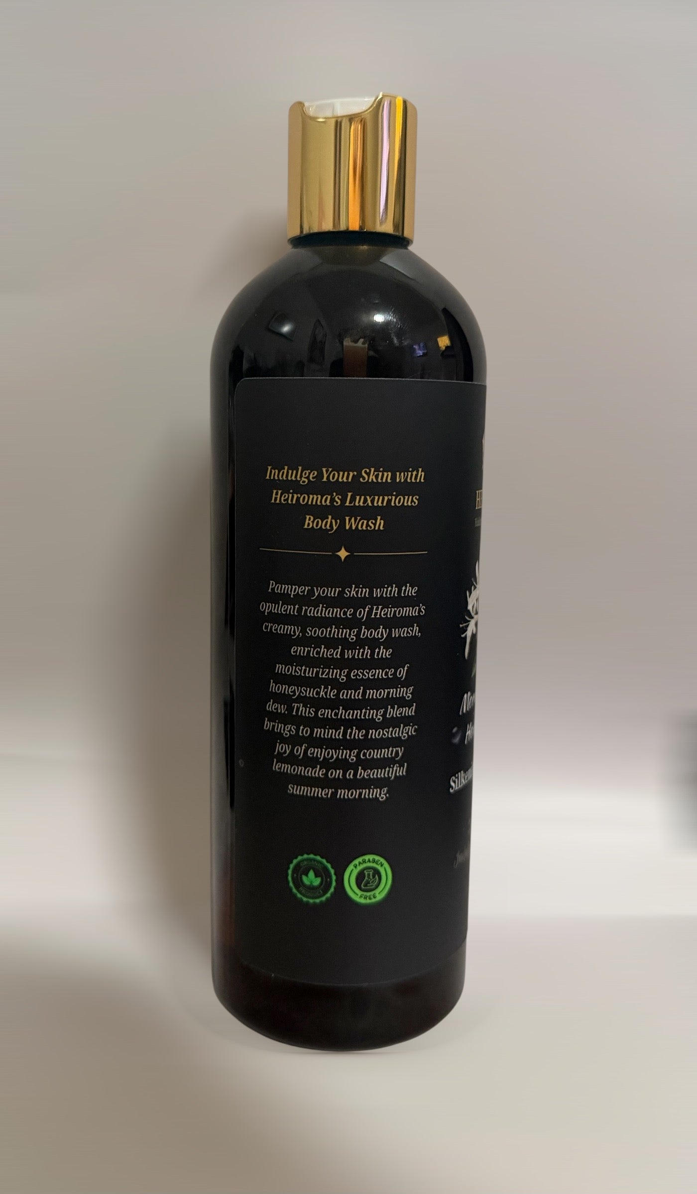 A black bottle of Heiroma's Silkening Body Wash with a metallic gold cap, shown from the back against a plain light gray background.